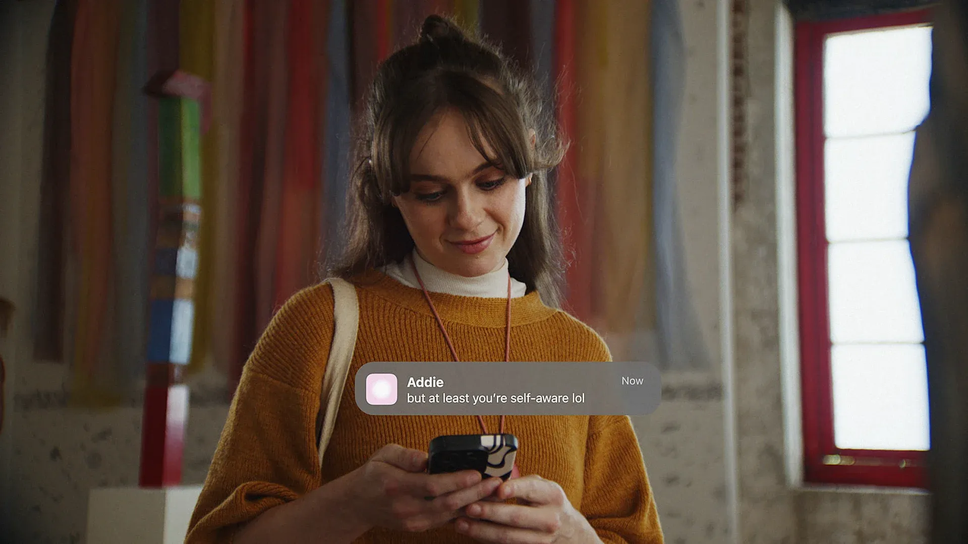 A woman read a text message from her Friend AI wearable.