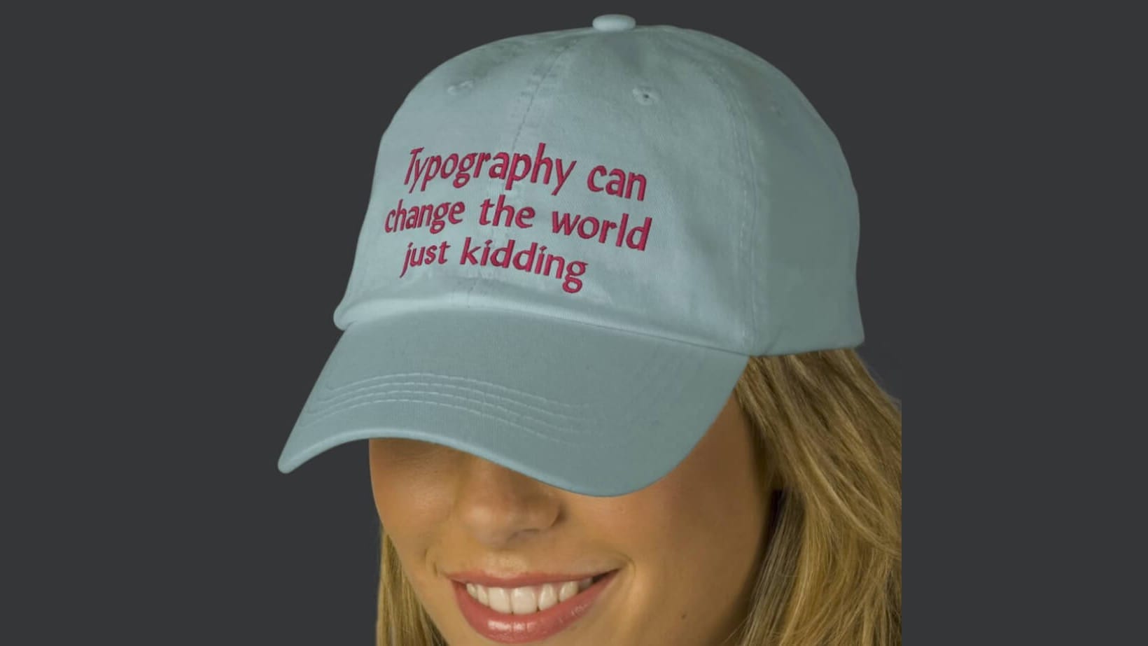 A woman wearing a custom embroidered hat saying, "Typography can change the world just kidding."